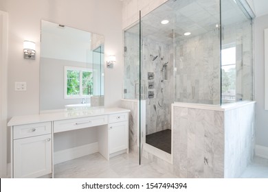 CHICAGO, IL, USA - AUGUST 28, 2019: A Bright Luxury Bathroom With A Large Shower And Small, White Vanity Counter Top. A Stand Alone Bath Tub Can Be Seen Through The Mirror With A View Outside.