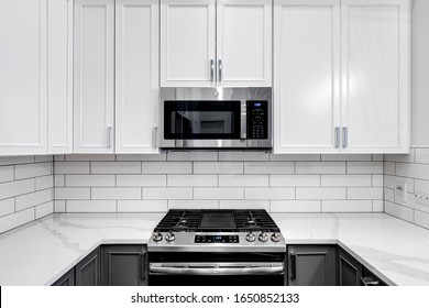 CHICAGO, IL, USA - DECEMBER 27, 2019: A detail shot of cabinets and stainless steel GE appliances in a small condo kitchen. The kitchen is fitted with white and grey cabinets with white subway tiles.