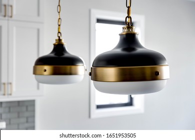 CHICAGO, IL, USA - JANUARY 4, 2020: Modern Black And Gold Light Fixtures Hanging In A White Kitchen With The Light Turn Off.