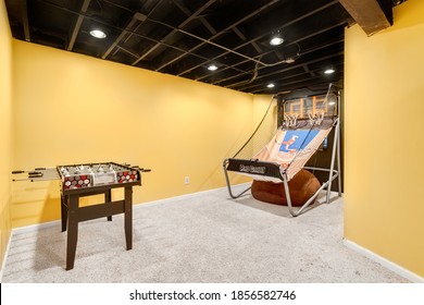 CHICAGO, IL, USA - JULY 11, 2019: A Yellow Walled Basement Game Room With Foosball And A Foldable Basketball Game. 