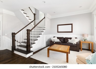 CHICAGO, IL, USA - JULY 16, 2021: A bright, furnished living room near a staircase with wood banisters and steps, white rails, and board and batten walls.