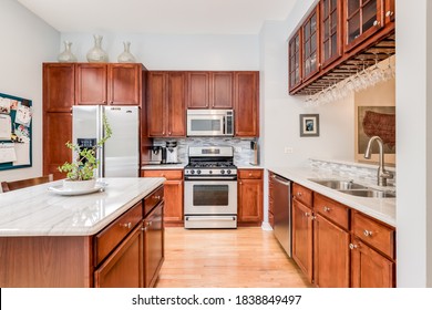 CHICAGO, IL, USA - JUNE 22, 2020: A Kitchen With Maple Wood Cabinets, A White Granite Counter Top, And Stainless Steel GE Appliances.