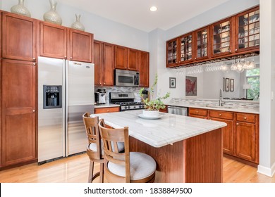 CHICAGO, IL, USA - JUNE 22, 2020: A Kitchen With Maple Wood Cabinets, A White Granite Counter Top, And Stainless Steel GE Appliances.