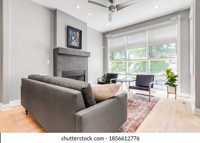 CHICAGO, IL, USA - JUNE 25, 2019: A Modern Living Room With A Stone Fireplace, Seating, High Ceiling, And Tall Windows.