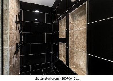 CHICAGO, IL, USA - JUNE 26, 2019: A Beautifully Renovated Shower With Black Marble Tiles, Brown Cut Out Shelves, And Black Hardware.