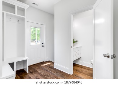 CHICAGO, IL, USA - JUNE 6, 2020: A Renovated White Mud Room Or Foyer Looking Towards A Coat Rack And Door With A White Bench And Coat Rack.