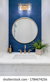 CHICAGO, IL, USA - JUNE 7, 2020: A Small Bathroom With Blue Wallpaper, Gold Hardware, And A White Marble Counter Top.