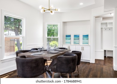 CHICAGO, IL, USA - JUNE 7, 2020: An Elegant, Modern Dining Room With Six Chairs And A Large Wooden Table Under A Fancy Gold Light Fixture.