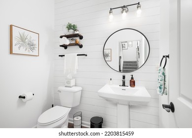 CHICAGO, IL, USA - MARCH 22, 2022: A Farmhouse Bathroom With A Shiplap Wall, Circular Mirror, And Pedestal Sink.