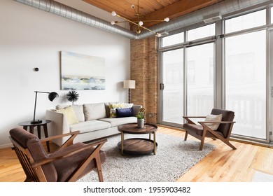 CHICAGO, IL, USA - MARCH 24, 2021: A Cozy Living Room With An Exposed Wood Ceiling, A Gold Sputnik Light Fixture Hanging Above, And Modern Seating On A Rug And Hardwood Floors.