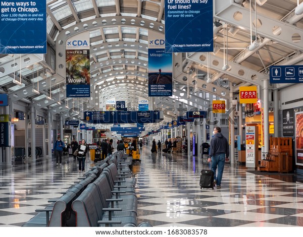 Chicago, IL / USA -\
March 24 2020: COVID-19 pandemic. A traveler in a face mask walks\
down the nearly deserted concourse at O’Hare airport on what would\
normally be a busy\
morning