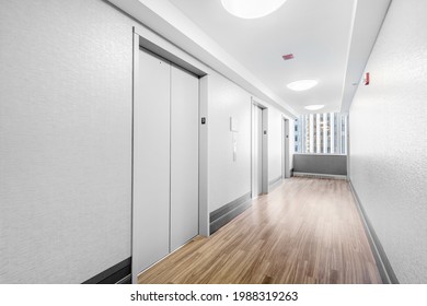 CHICAGO, IL, USA - OCTOBER 8, 2020: A High Rise Hallway With White Wallpaper And Elevator Doors, Wood Flooring, And A View To The City.