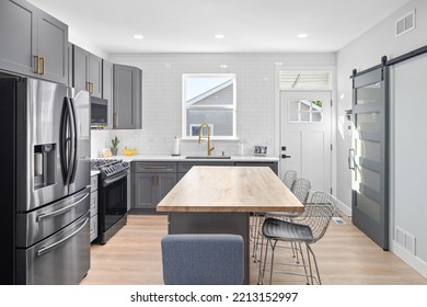 CHICAGO, IL, USA - SEPTEMBER 1, 2022: A Kitchen With Dark Grey Cabinets, Large Island With A Wood Countertop, And Stainless Steel Appliances.