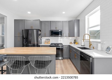 CHICAGO, IL, USA - SEPTEMBER 1, 2022: A Kitchen With Dark Grey Cabinets, Large Island With A Wood Countertop, And Stainless Steel Appliances.