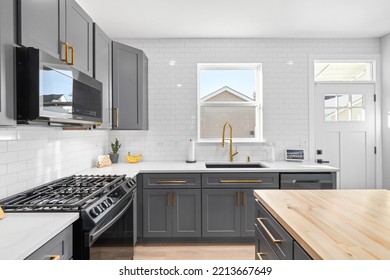 CHICAGO, IL, USA - SEPTEMBER 1, 2022: A Kitchen With Dark Grey Cabinets, Large Island With A Wood Countertop, And Stainless Steel Appliances.