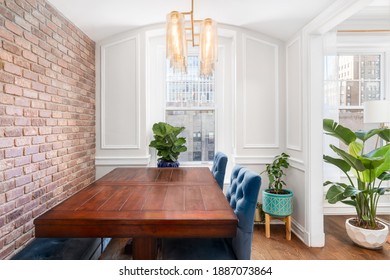 CHICAGO, IL, USA - SEPTEMBER 7, 2019: A Beautiful Dining Room With A Wooden Table, Exposed Brick Wall, Fancy Gold Light Fixture, And A View Out To The City.