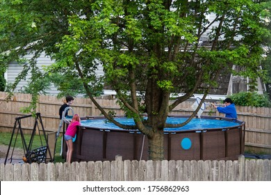 CHICAGO, ILLINOIS - June 6, 2020: Family Setting An Above Ground Pool In Backyard Self Distancing During The Covid19 Pandemic