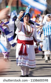 Chicago, Illinois, USA - April 29, 2018  Greek woman wearing traditional clothing waving the  greek flag at the Greek Independence  Day Parade