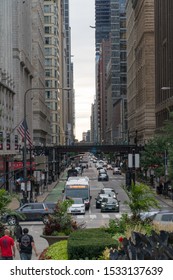 Chicago, Illinois, USA - Circa 2019: Vertical View Down Street In Downtown Chicago During Day Time Morning Commute Past  L  Train Track Overhead Loop Street