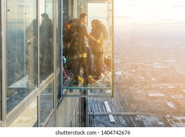 Chicago, Illinois, USA, October 2016: A Group Of Tourists Enjoying The Panoramic View Seen From The Transparent Glass Ledges On The 103rd Floor Of The Willis Tower Sky Deck Observatory In Chicago