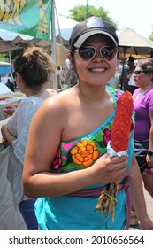 CHICAGO - JULY 2021: Smiling Young Woman Holds Elote Or Mexican Street Corn At Latino Hispanic  Street Fair Food Festival In July 2021 In Chicago. The Festival Celebrates Latino Food And Heritage.