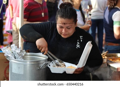 CHICAGO - MAY 27: Server Fills Carry Out Box At Mole De Mayo Festival On May 27 2017 In Chicago. A Woman Places Cooked Chicken Into A Carryout Box At A Mexican Street Fair.