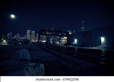 Chicago Skyline At Night With Train Tracks Leading Into The City.
