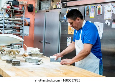 Chicago,IL/USA-July 1st 2019: Hispanic Male Blue Collar Bakery Chef Worker Is In The Process Of Kneeing Dough And Various Ingredients For His Pastry Shop. Local Homemade Desserts Are Cooked Perfectly