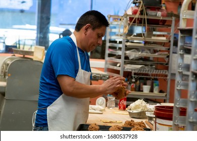 Chicago,IL/USA-July 1st 2019: Hispanic Male Blue Collar Bakery Chef Worker Is In The Process Of Kneeing Dough And Various Ingredients For His Pastry Shop. Local Homemade Desserts Are Cooked Perfectly