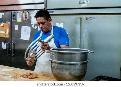 Chicago,IL/USA-July 1st 2019: Hispanic Male Blue Collar Bakery Chef Worker Is In The Process Of Kneeing Dough And Various Ingredients For His Pastry Shop. Local Homemade Desserts Are Cooked Perfectly