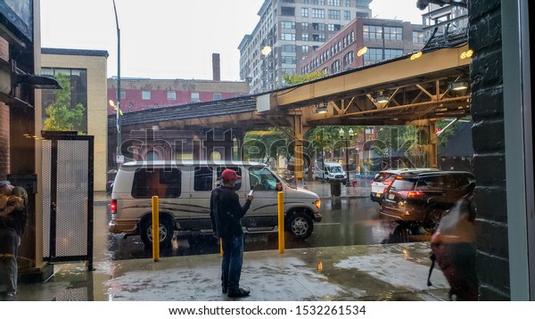 Chicago,IL/USA-October 11th 2019:A vertical\
image of a man walking in the rain during a light shower in Chicago\
metropolitan area near the train tracks. the man is soaked as he\
seeks\
shelter.
