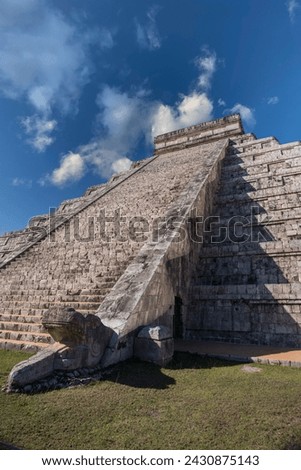 Chichen Itza's castle, view from below the pyramid, with a close-up of the Quetzalcoatl serpent carved in stone on a sunny day