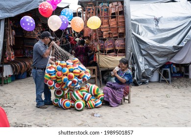 Chichicastenango, Guatemala - October 10, 2019: Mayan man and woman are selling rubber balls and balloons in the Chichicastenango market.