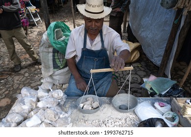 Chichicastenango, Guatemala - October 10, 2019: The gentleman is weighing and selling stones at the market in Chichicastenango.