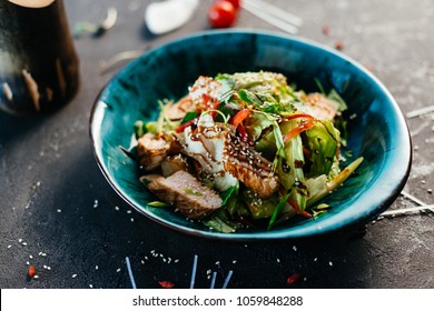 Chicken asian salad served in blue plate on dark background