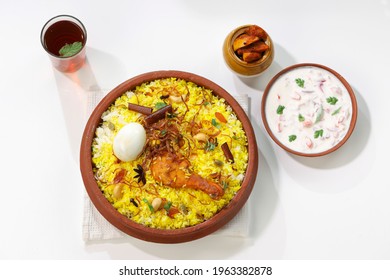 Chicken Biryani , Kerala Style Chicken Dhum Biriyani  Arranged Traditionaly In An Earthen Ware Lined With Banana Leaf,raitha  And Lemon Tea As Side Dish On White Background, Selective Focus.