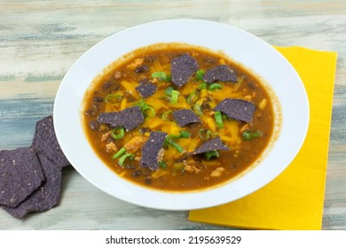 Chicken And Black Bean Soup With Blue Corn Tortilla Chips In White Bowl With Yellow Napkin