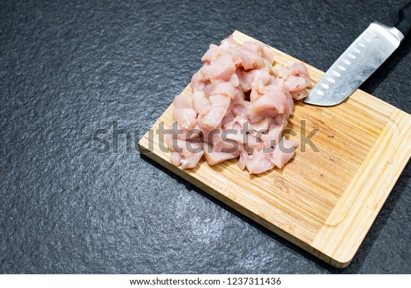 chicken breast divided in half on a\
wooden cutting board. Chicken to cook in light recipes for a diet.\
Whole chicken breasts chopped in small pieces by\
knife
