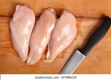 Chicken Breast And Knife On Wooden Cutting Board. Directly Above.