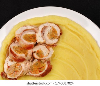 Chicken breast rolls with mashed potatoes on a white plate and black background.Top view.