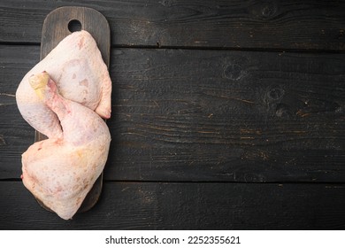 Chicken brow and drumstick with skin set, on wooden cutting board, on black wooden table, top view flat lay, with copy space for text