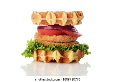 chicken burger waffle sandwich with lettuce tomato and onion on white