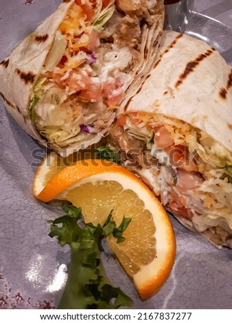 Chicken, Cheese and Vegetable Wrap presented with Orange and Lettuce on a Plate