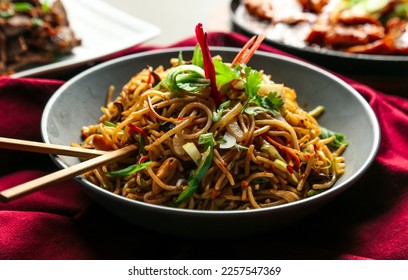 Chicken chowmein Hakka noodles or Schezwan or Szechwan noodles served in a bowl with chopsticks. selective focus - Shutterstock ID 2257547369