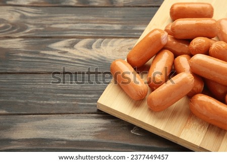 Chicken cocktail sausage on cutting board on brown wooden background. Space for text. Top view