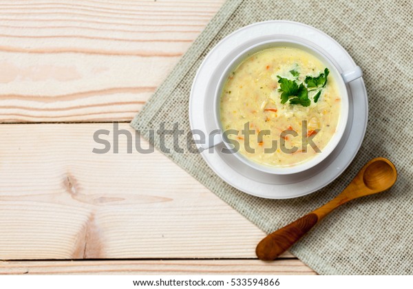 Chicken and coconut milk\
soup on an old rustic wooden table with burlap napkin, top view,\
copy space