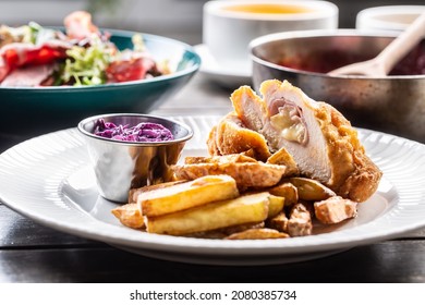 Chicken Cordon Bleu With Ham And Cheese Inside Served With Fried Potato Wedges And Red Cabbage Salad.