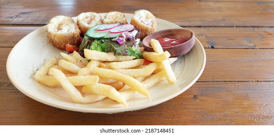 Chicken Cordon Bleu Served With Petit Peas And Baby Corn Salad With Herb Fries And Chili Dipping Sauce, On A Wooden Rustic Table 