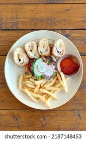 Chicken Cordon Bleu Served With Petit Peas And Baby Corn Salad With Herb Fries And Chili Dipping Sauce, On A Wooden Rustic Table 