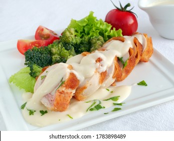 Chicken cordon bleu sliced with parmesan cream sauce and vegetables